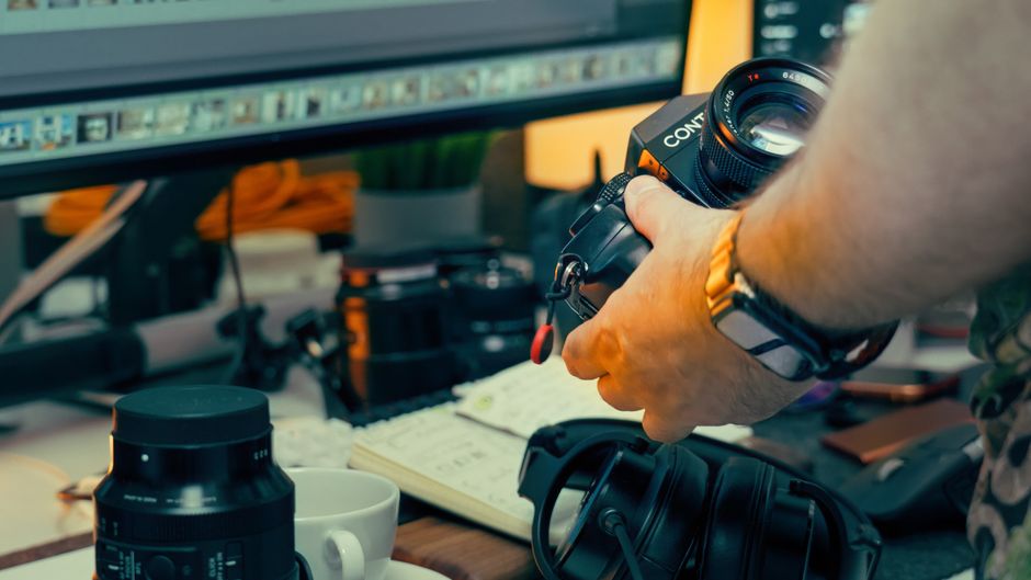 An artistic desk setup featuring vintage camera gear, monitors, and headphones, perfect for a creative photography workflow.