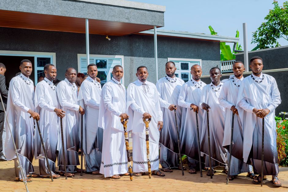 A group of men wearing traditional white robes holding staffs outdoors.